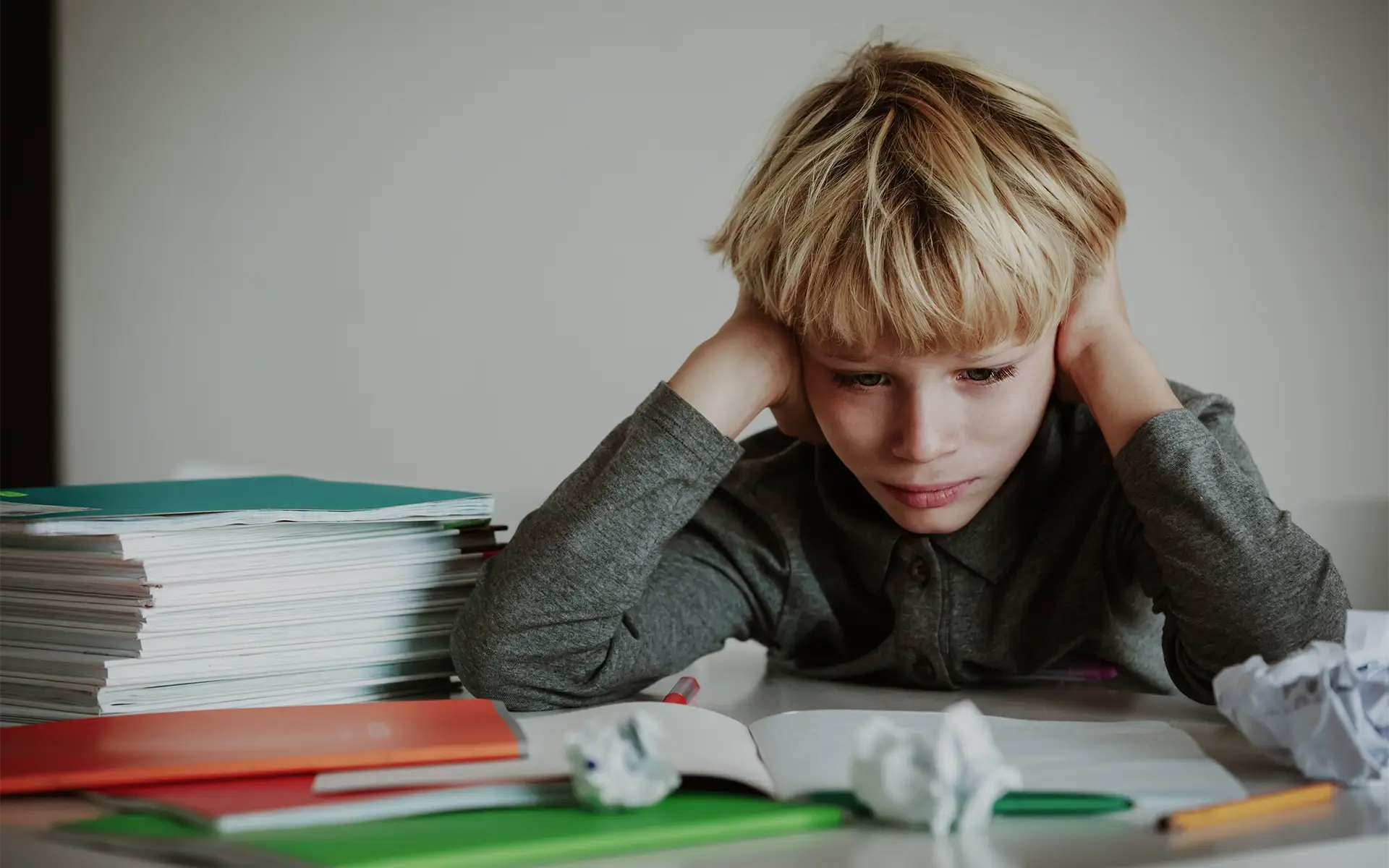 A boy sitting at his desk stressed because of lots of homework