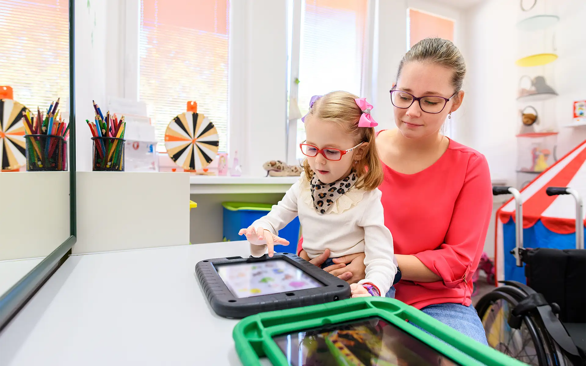 A therapist holding a child who is playing with a tablet