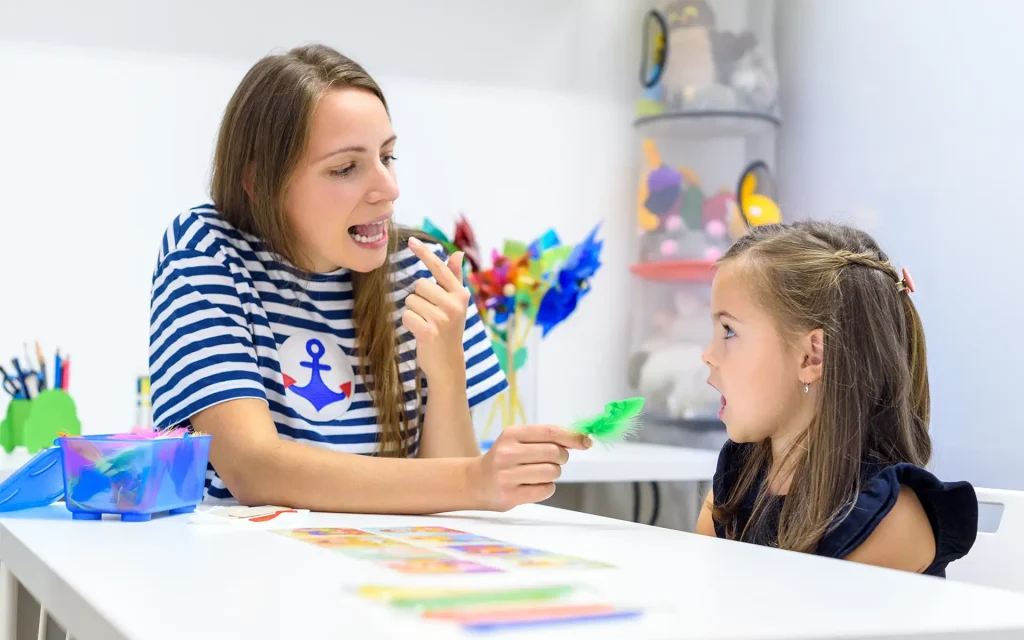 A young girl working on pronunciation with a female speech language therapist