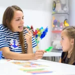 A young girl working on pronunciation with a female speech language therapist