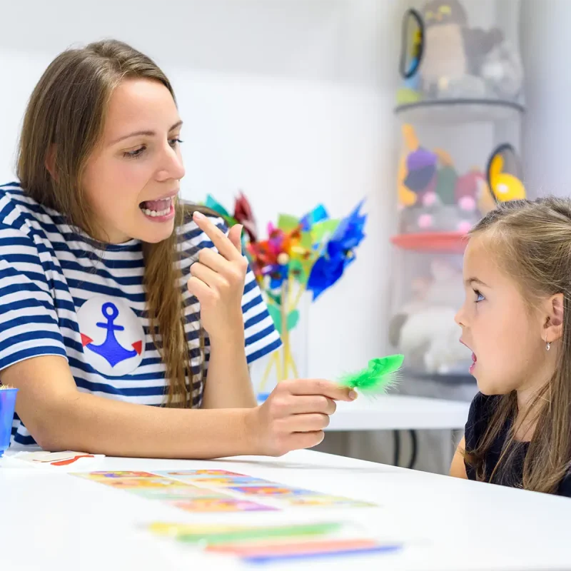 A young girl working on pronunciation with a female speech language therapist