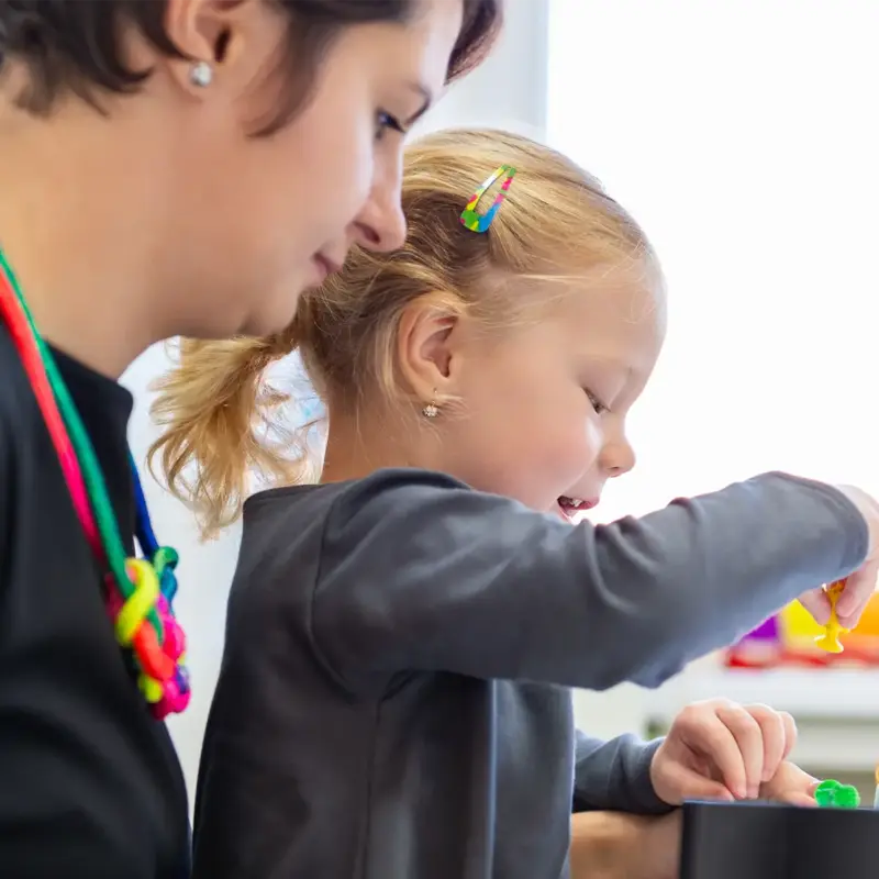 A girl in child occupational therapy session doing sensory exercises with her therapist